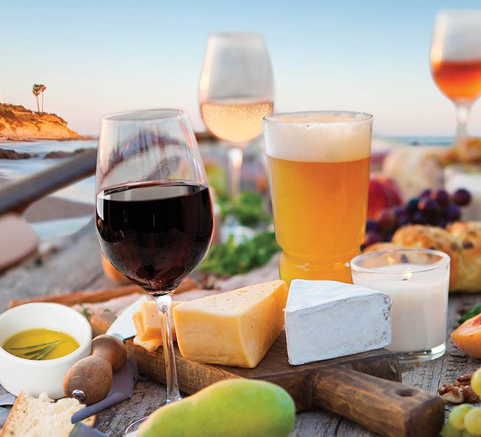 Cheese, wine, beer, and olive oil on a table at the beach