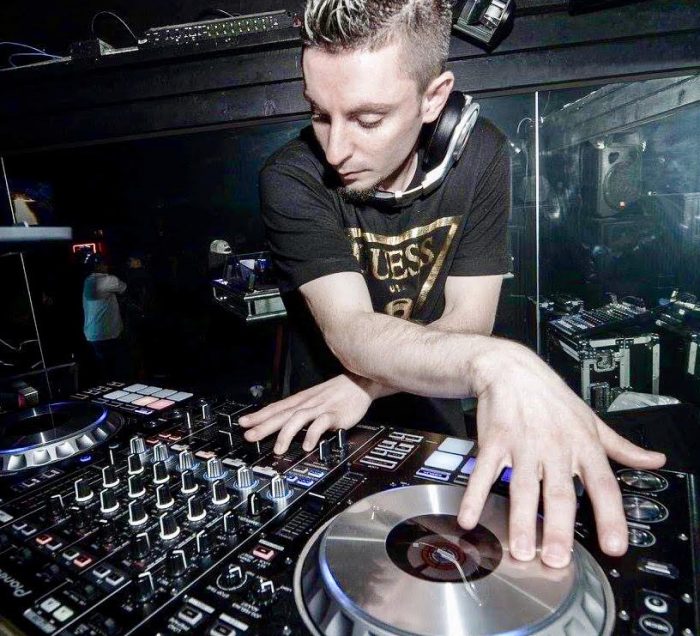 A man djing with his arms crossed over a turntable