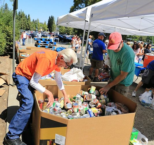 People organizing Food Donations in a large box for Smud Giving Mondays at the Fair