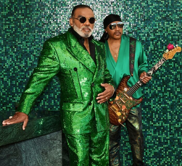 The Isley Brothers wearing green standing against a green tile backdrop