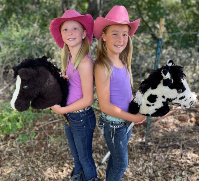 two little girls in pink hats with toy horses