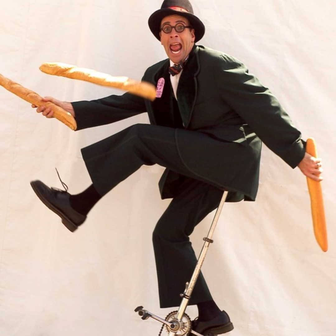 Man juggling bread on a unicycle.